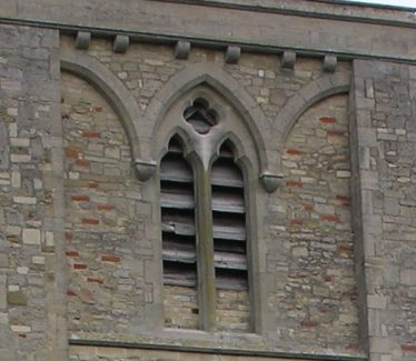 The two-light window with a quatrefoil above in the upper stage of the tower marks the beginning of patterns in stone to decorate window openings. The steeply-pointed profile of the arch and cusped heads to the lancets are typical of the later 13th century. The window has been completely rebuilt during restoration in the 1960s. | Peter Draper